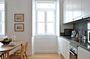 Una cocina moderna con armarios blancos, una mesa de comedor de madera y un ventanal.