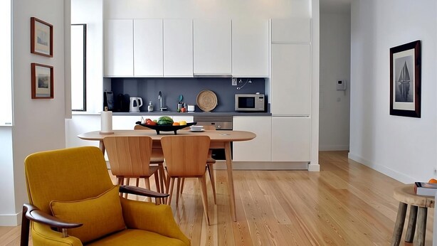 Une cuisine moderne avec des meubles blancs, un four à micro-ondes et un panier de fruits posé sur le plan de travail.