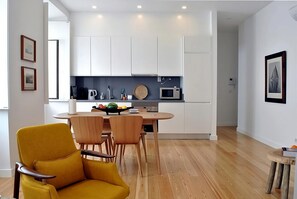 Una cocina moderna con armarios blancos, un microondas y un frutero sobre la encimera.