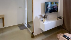 A modern living room with a TV mounted on the wall, a sofa, a coffee table, and a decorative mirror. - Grand Studio (Abidjan)