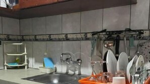 A kitchen with a sink, cabinets, and a dish rack. - Grand Studio (Abidjan)