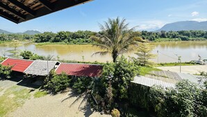 A view of a river with a bridge overhead, surrounded by greenery and mountains in the background. - Kingkham Riverside Hotel (Luang Prabang)