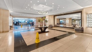 A spacious lobby with a reception desk, a chandelier, and a seating area. - Bayfront High-Rise Condo | Oceanview | StayCozy (Miami)