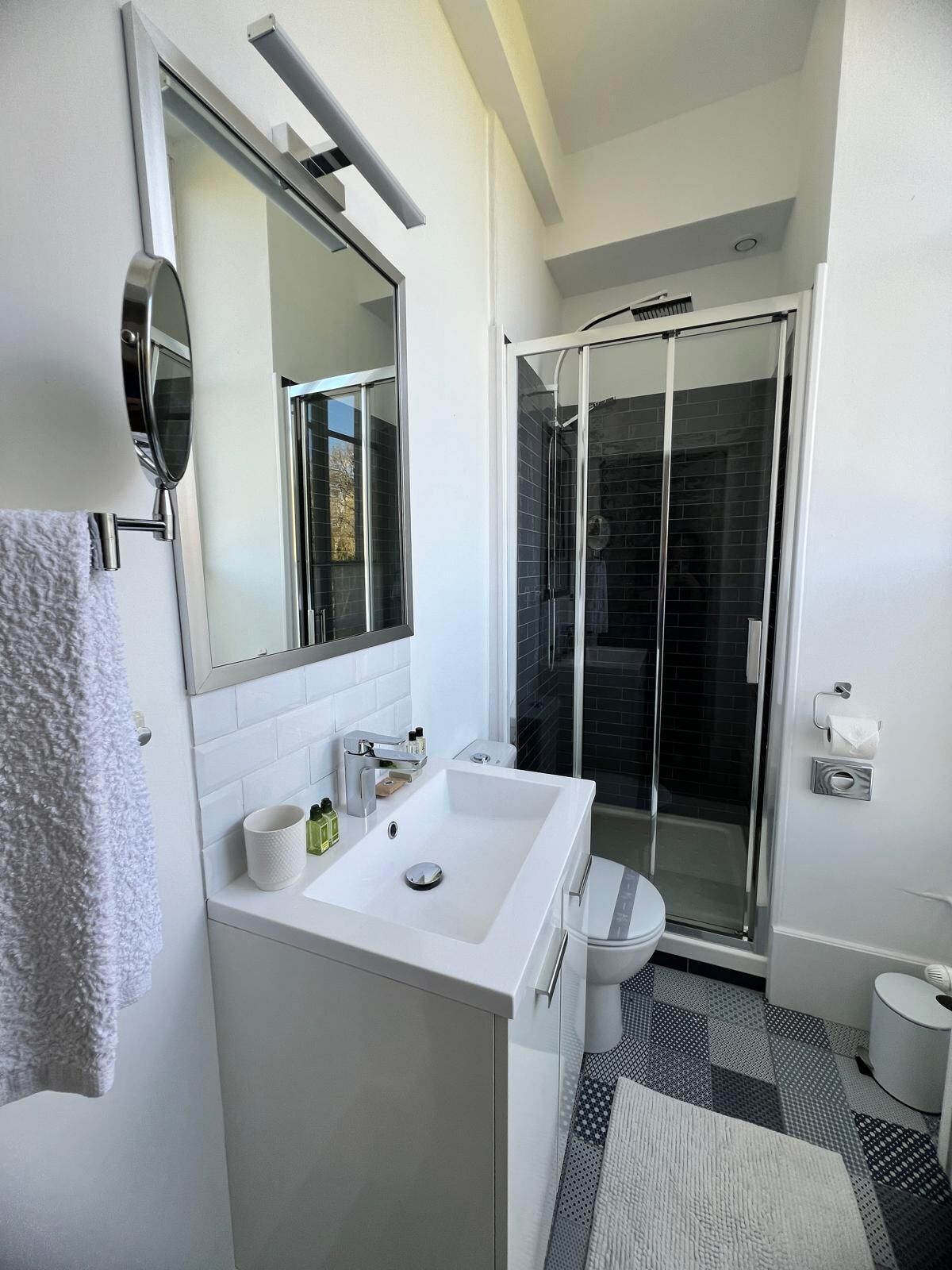 A modern bathroom with a white sink, mirror, and shower.
