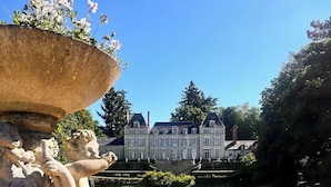 A classical garden with a large fountain, manicured lawns, and a stately building in the background. - Château du Rondon (Olivet)