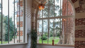 A spacious room with a large window, a wooden ceiling, and a view of a tree. - Château du Rondon (Olivet)