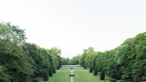 A formal garden with a symmetrical layout, featuring neatly trimmed hedges, a central pathway, and a seating area with outdoor furniture. - Château du Rondon (Olivet)