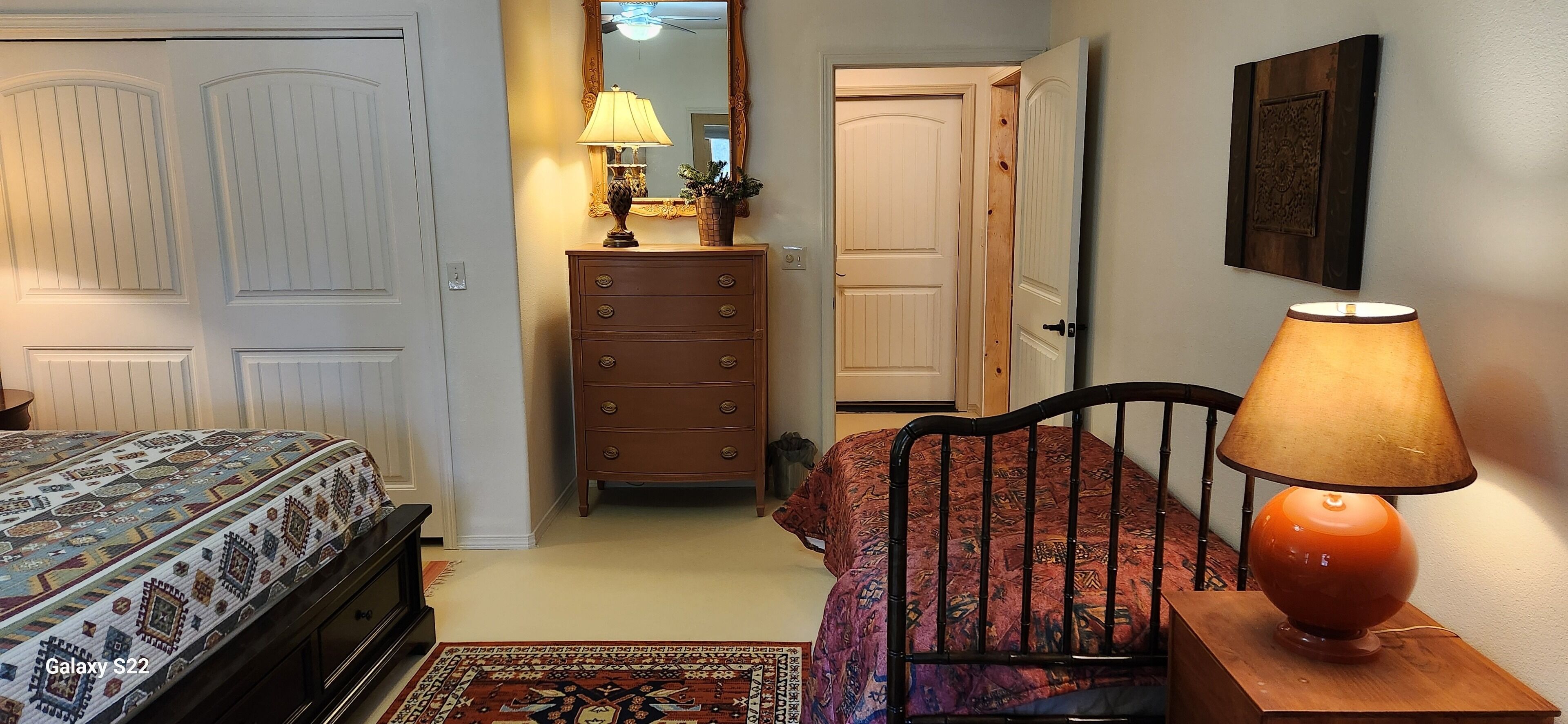 Un dormitorio con cama, cómoda, lámpara y espejo.