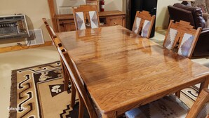 Un coin repas avec une table et des chaises en bois, un extincteur et un réfrigérateur noir.