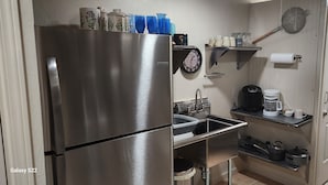 Une cuisine compacte équipée d’un réfrigérateur en acier inoxydable, d’un évier, d’une machine à café et de divers ustensiles de cuisine.