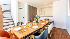 Un comedor con una mesa de madera dispuesta para una comida, una escalera y una puerta que da a otra habitación.