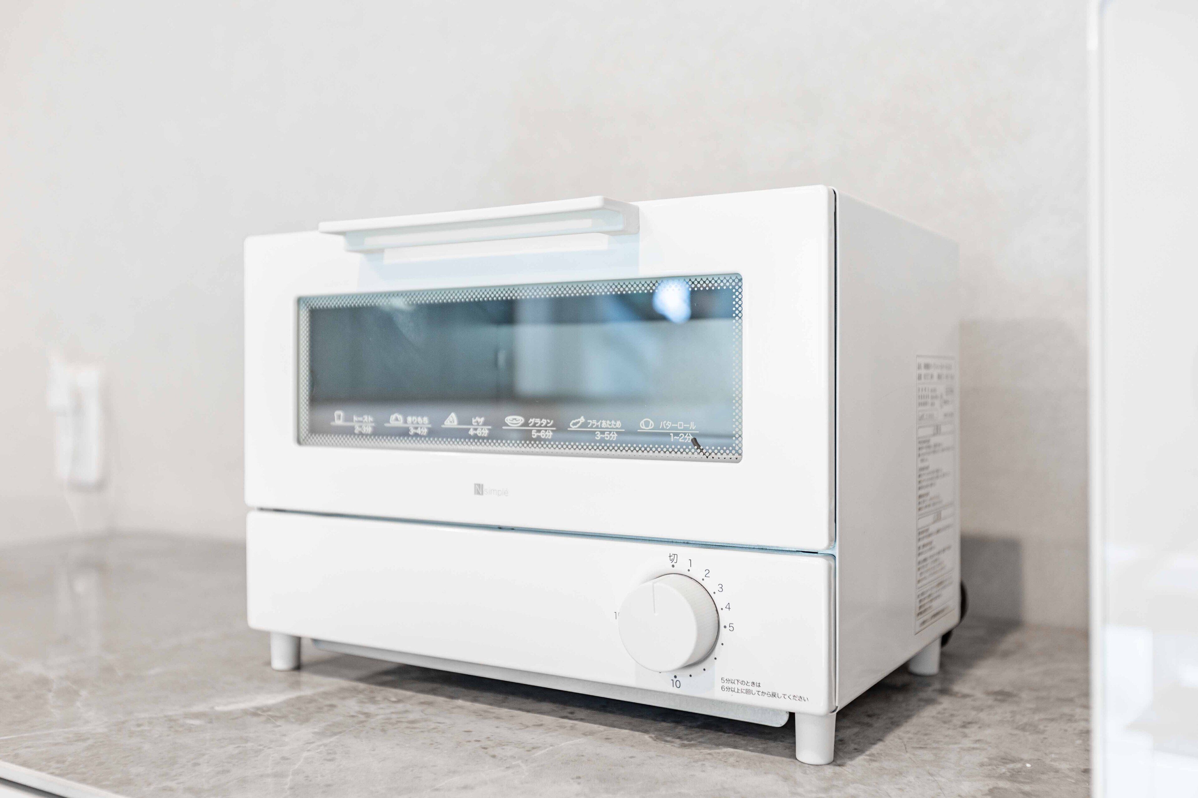 A white portable heater with a digital display and a control knob, placed on a marble countertop.