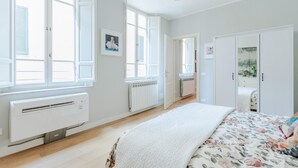 A bedroom with a bed, a radiator, a window, and a door. - Miss Penny in Lucca With 2 Bedrooms and 1 Bathrooms (Lucca)