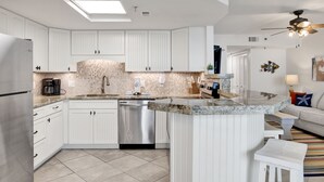 A modern kitchen with white cabinetry, a dishwasher, and a granite countertop. - Beachfront 1BR @ Phoenix III • Sleeps 4 • Stunning Views, Balcony, Pools & Beach Access (Orange Beach)