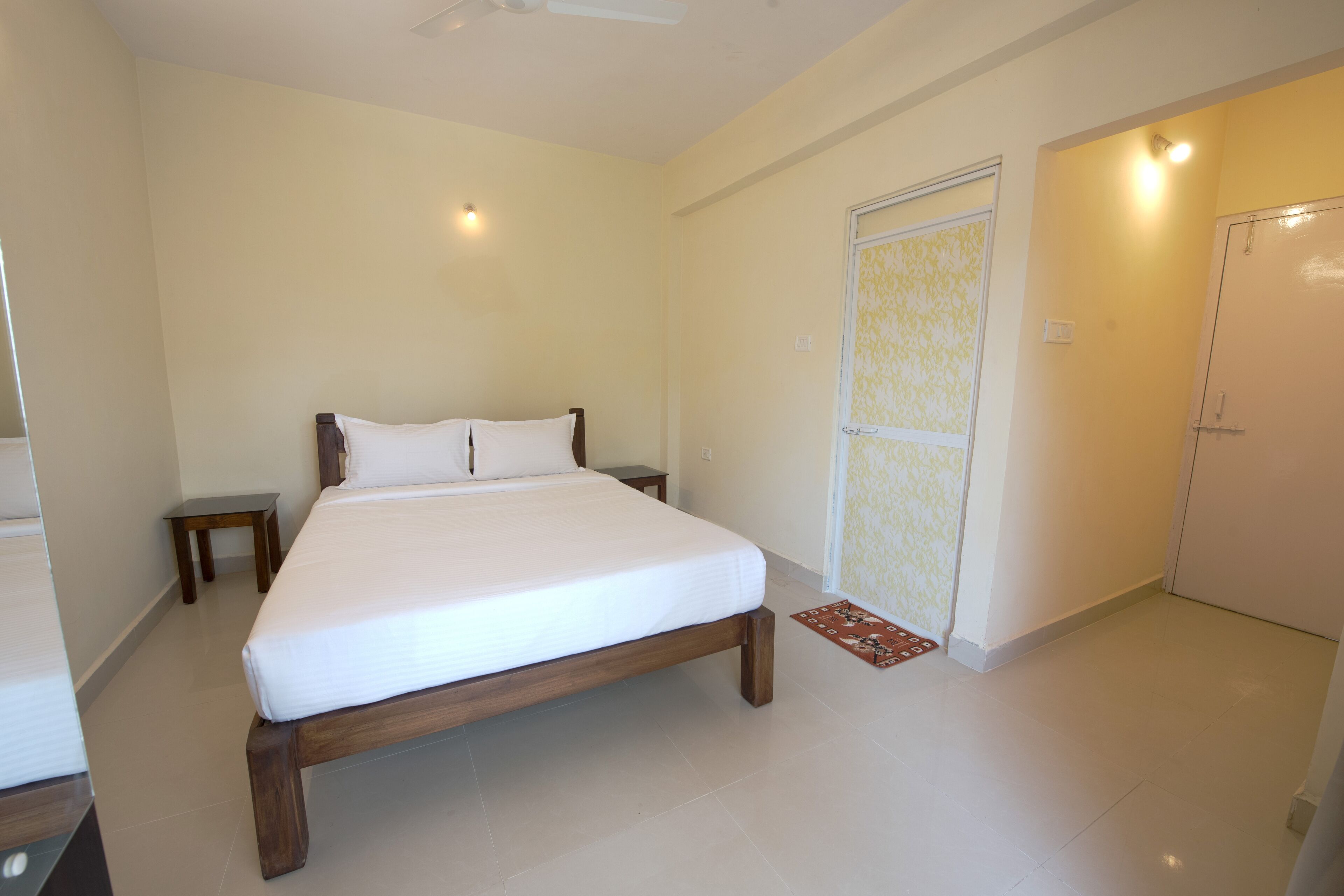 A bedroom with a bed, bedside tables, a wardrobe, and a door with a patterned curtain.