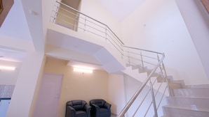 Un interior amplio con una escalera moderna, dos sillones de cuero negro y una puerta.