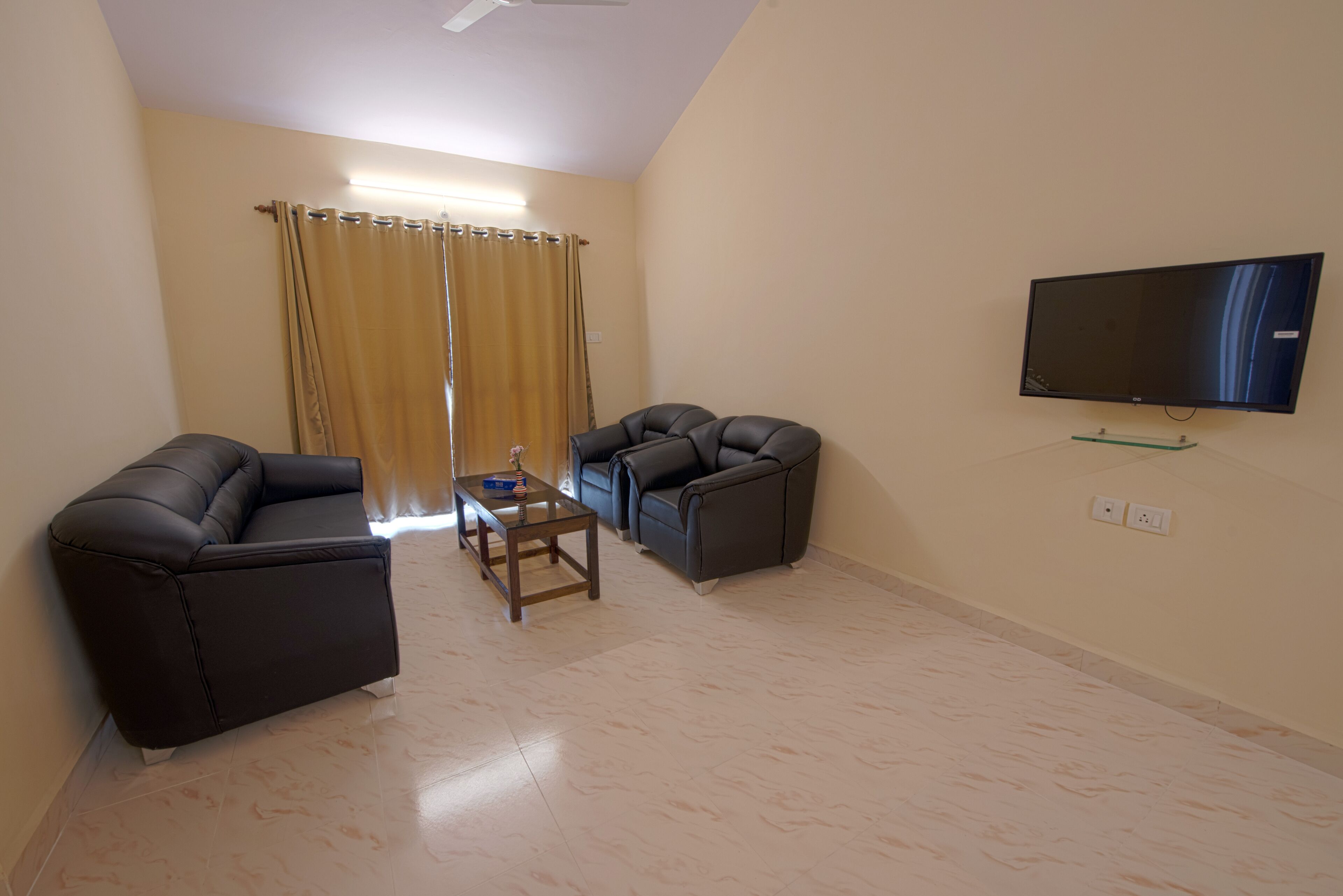 A living room with two sofas, a coffee table, and a flat-screen TV mounted on the wall.