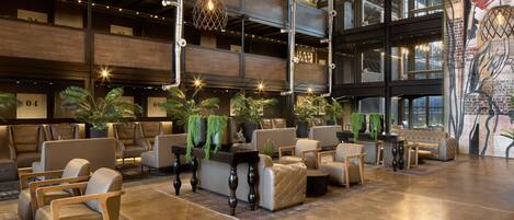 A spacious lobby with multiple seating areas, a reception desk, and a large mural on the wall.