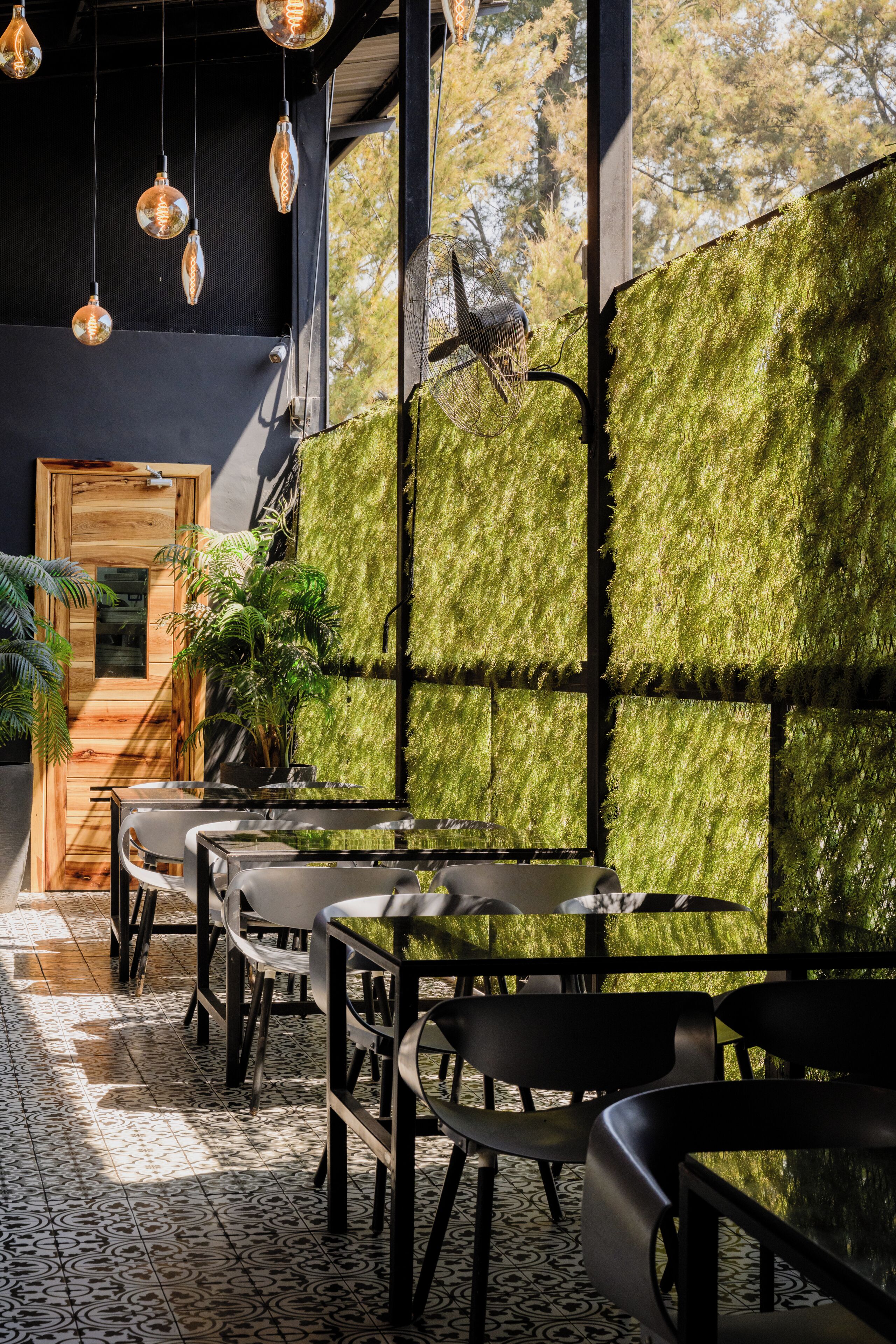 A modern interior with a seating area, a wooden door, and a wall covered in green moss.