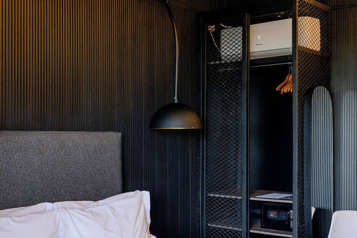 A hotel room with a large bed, a desk, a chair, and a wardrobe.