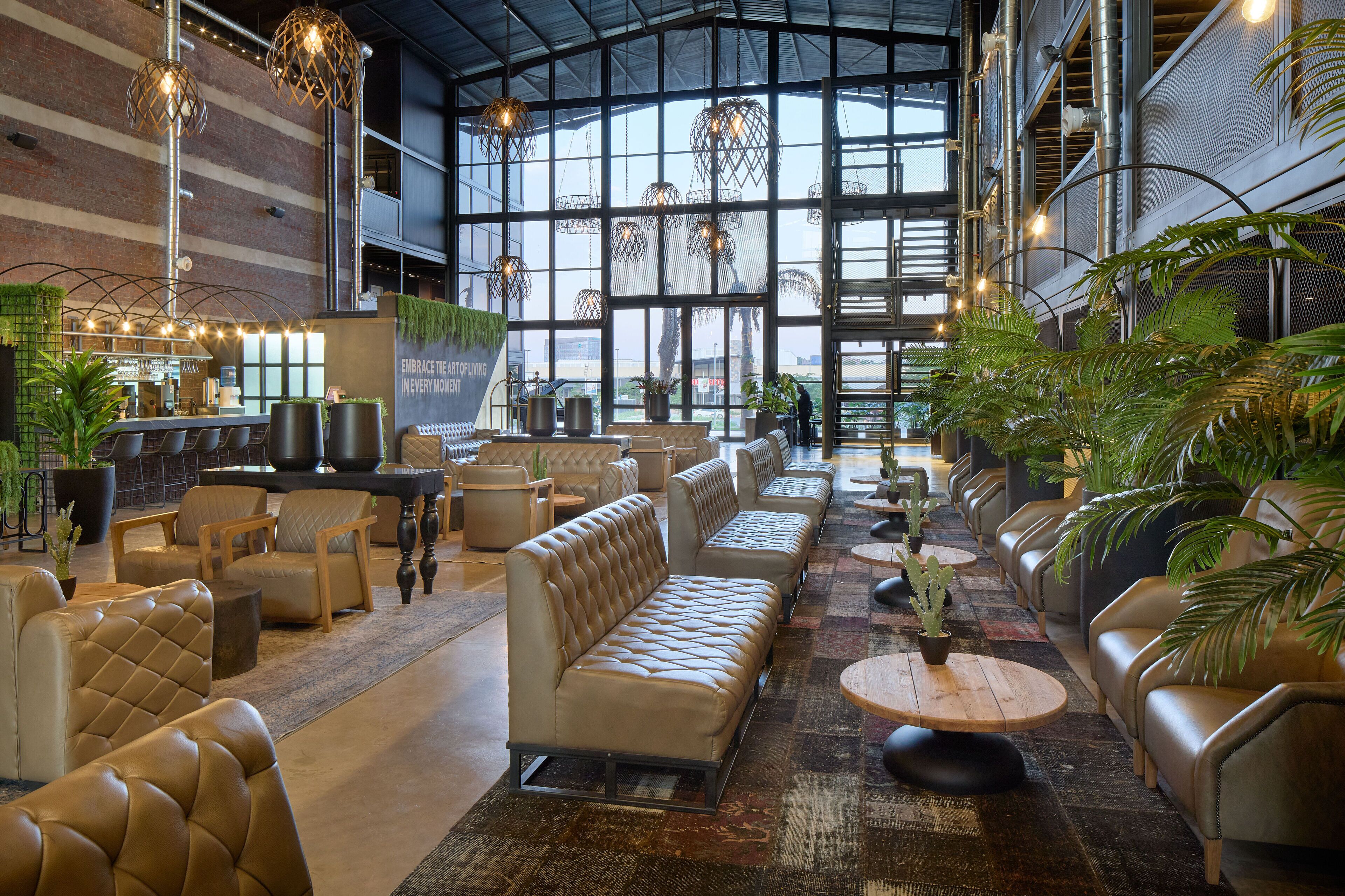 A spacious lobby with leather sofas, a bar area, and large windows allowing natural light.