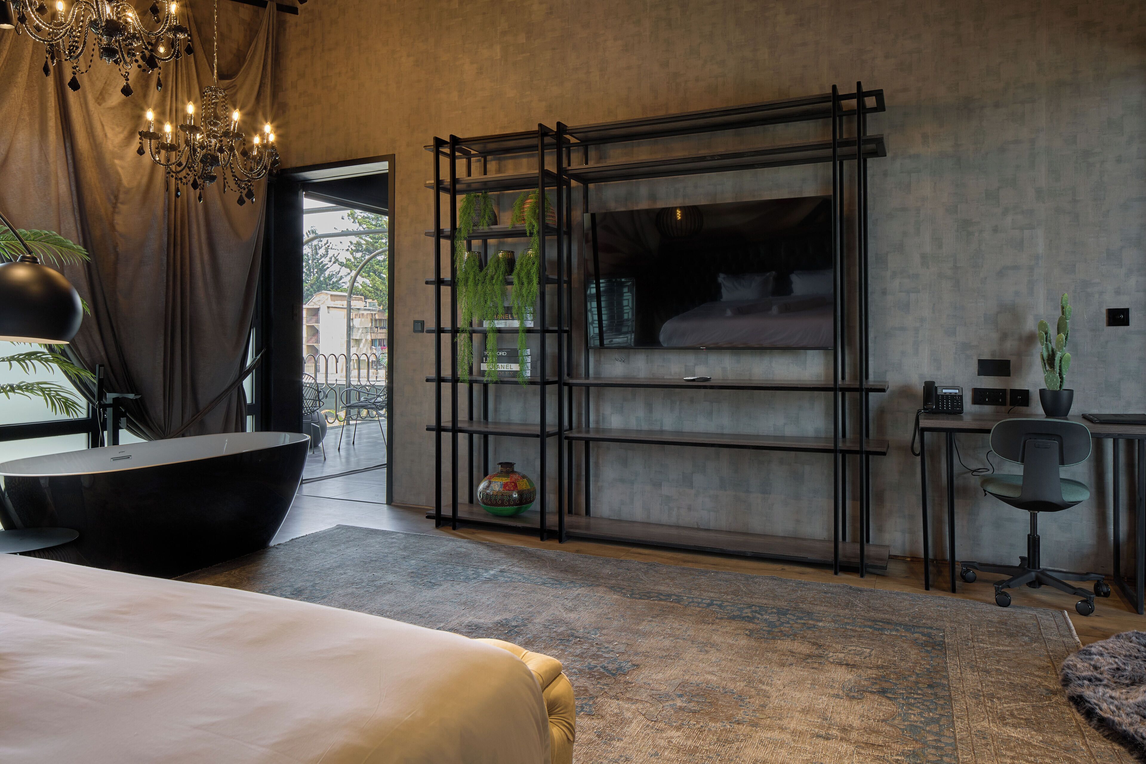 Una camera da letto moderna con un letto grande, televisione integrata, una scrivania nera e un'ampia finestra.