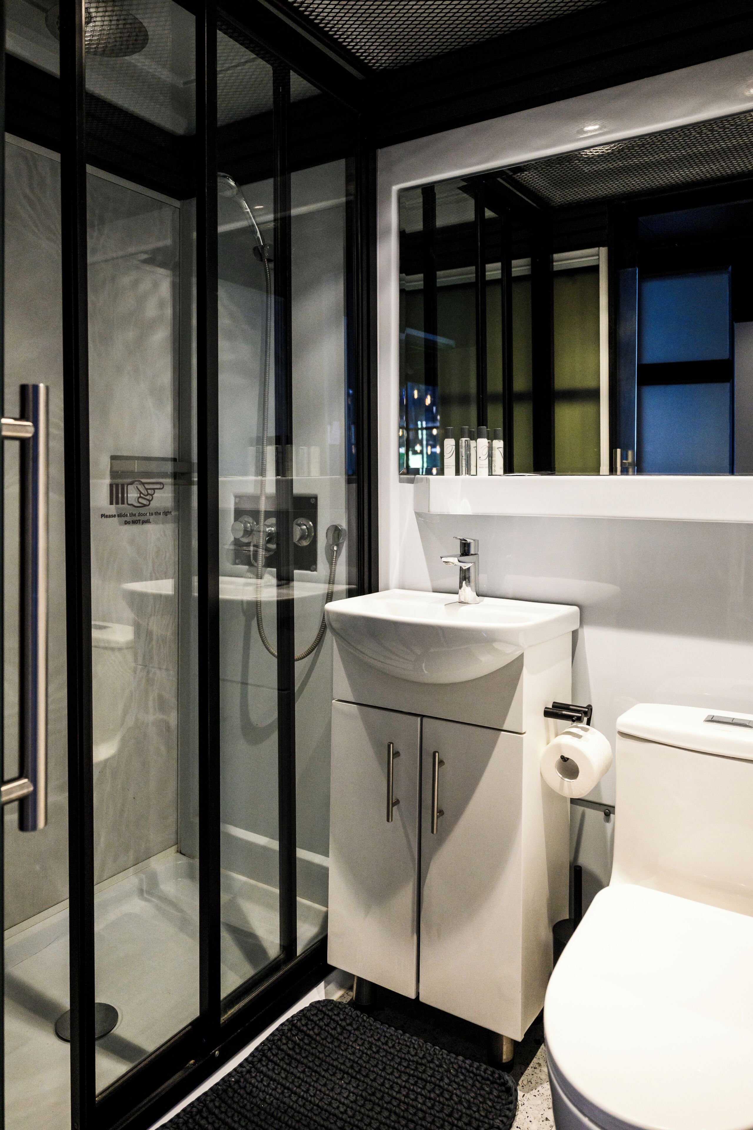 A modern bathroom with a glass-enclosed shower, a white sink, and a toilet.