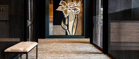 Un pasillo con un banco, un muro decorativo con estampado floral y un suelo con diseño.