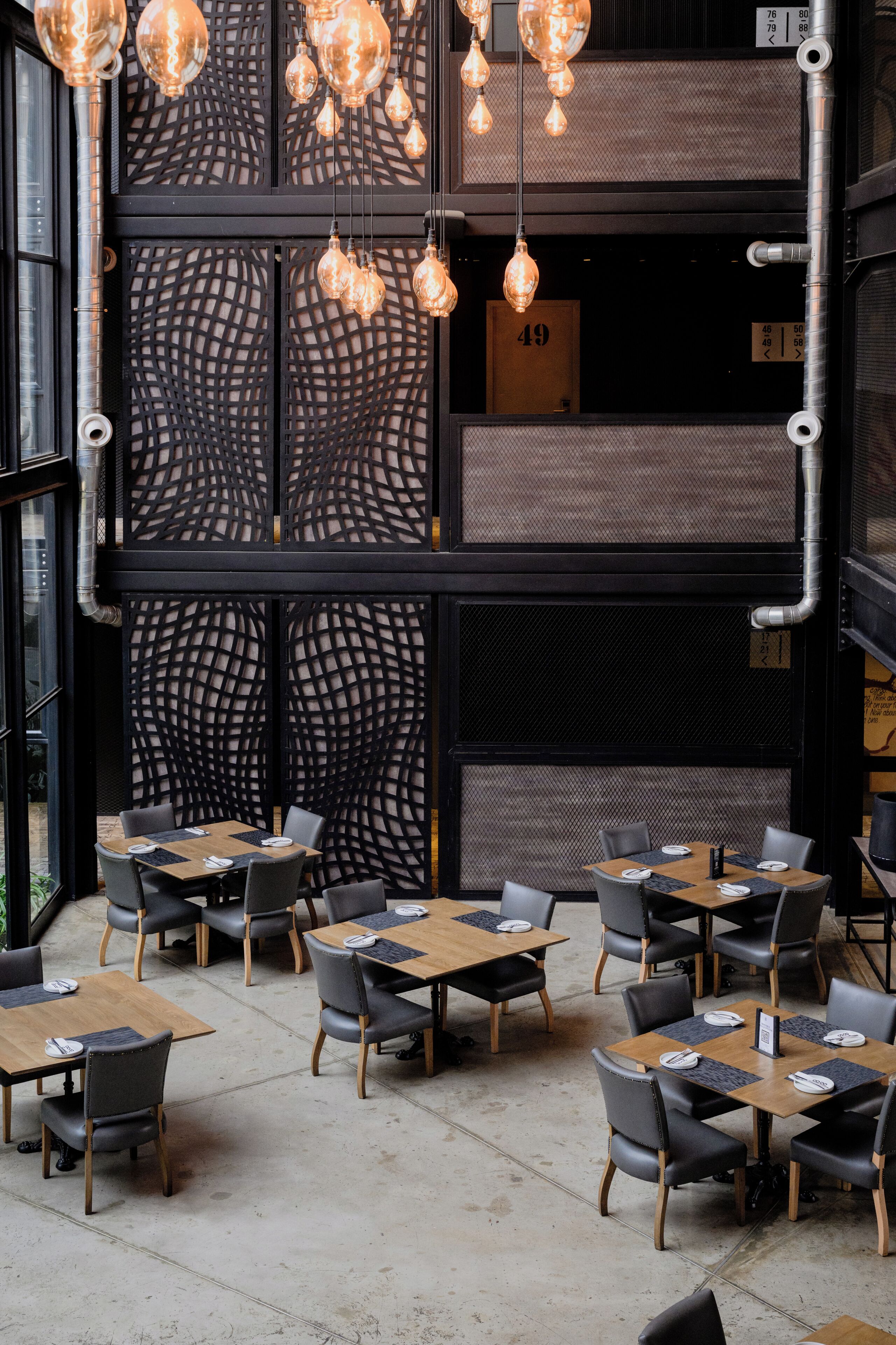 Un restaurante con varias mesas y sillas, una pared decorativa con un número y lámparas colgantes.