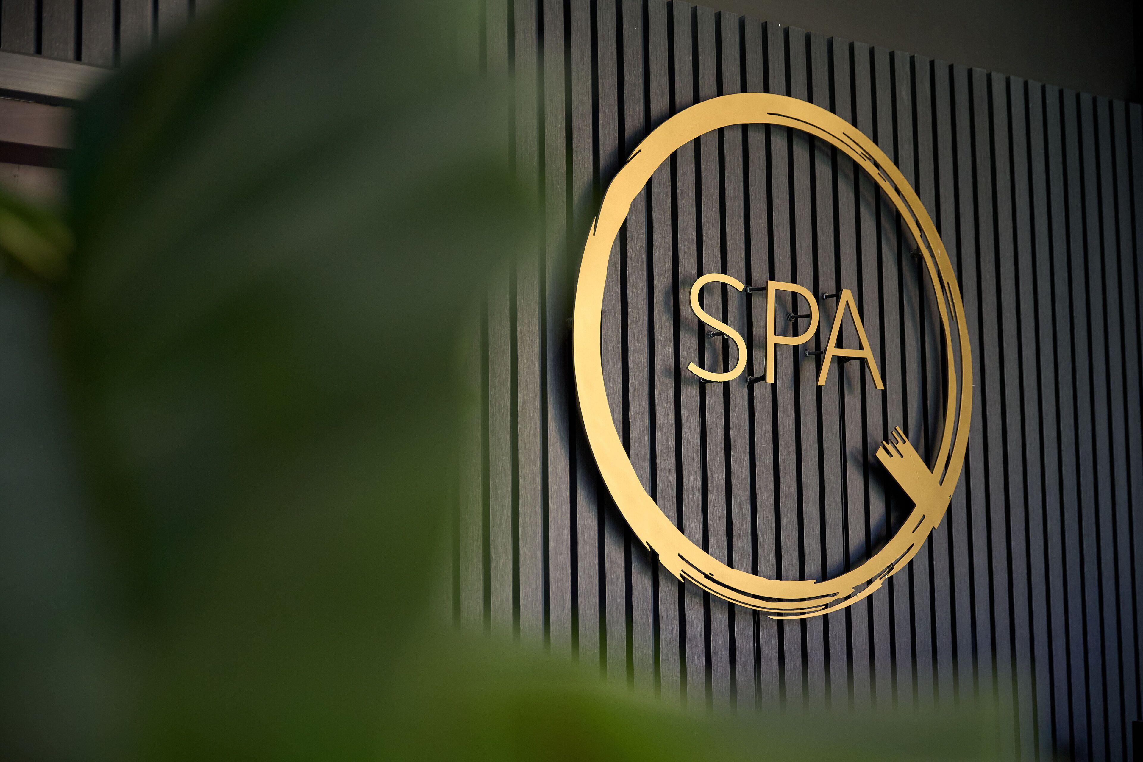 A wall-mounted sign with the letters "SPA" in a gold circle, indicating a spa facility.