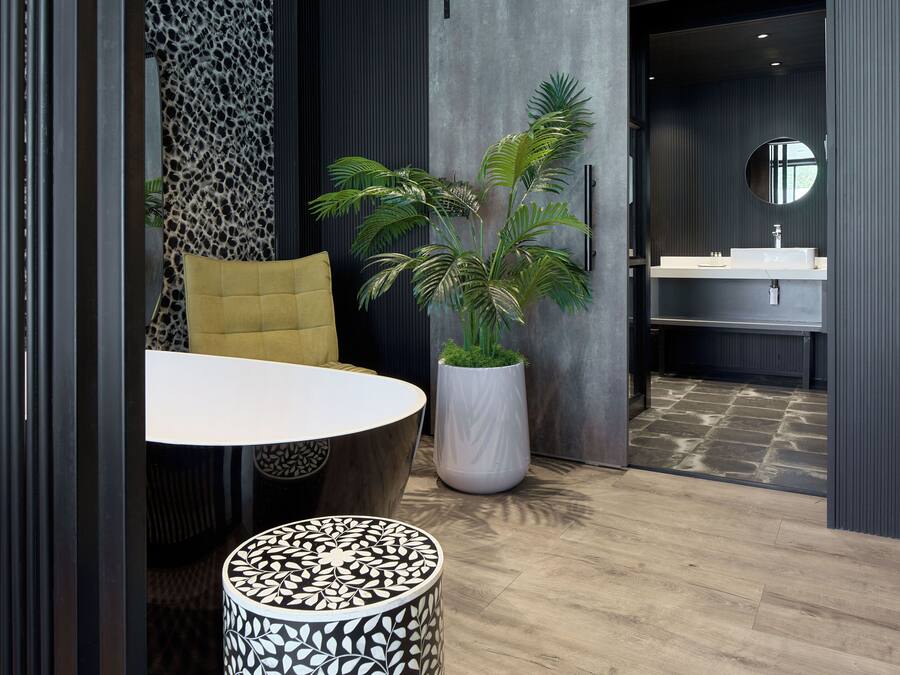 A modern bathroom with a large mirror, a sink, and a potted plant.