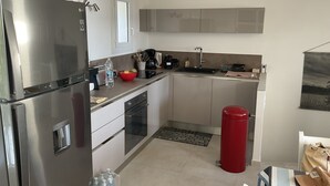 A modern kitchen with stainless steel appliances, a red trash bin, and a sink. - Xxxxxxxxxx (Sainte-Maxime)