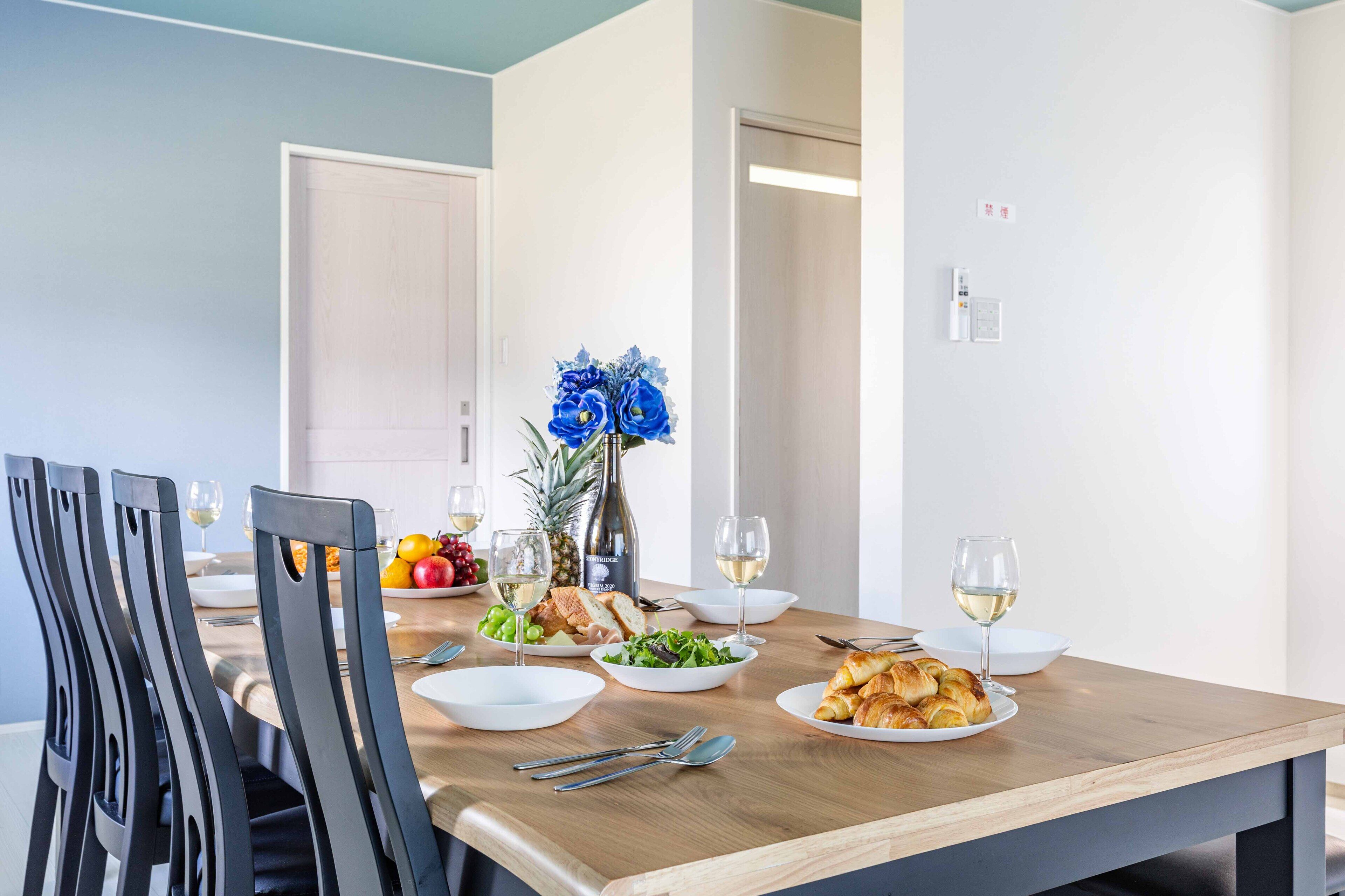 A dining table set with plates of food, glasses of wine, and a vase of flowers.
