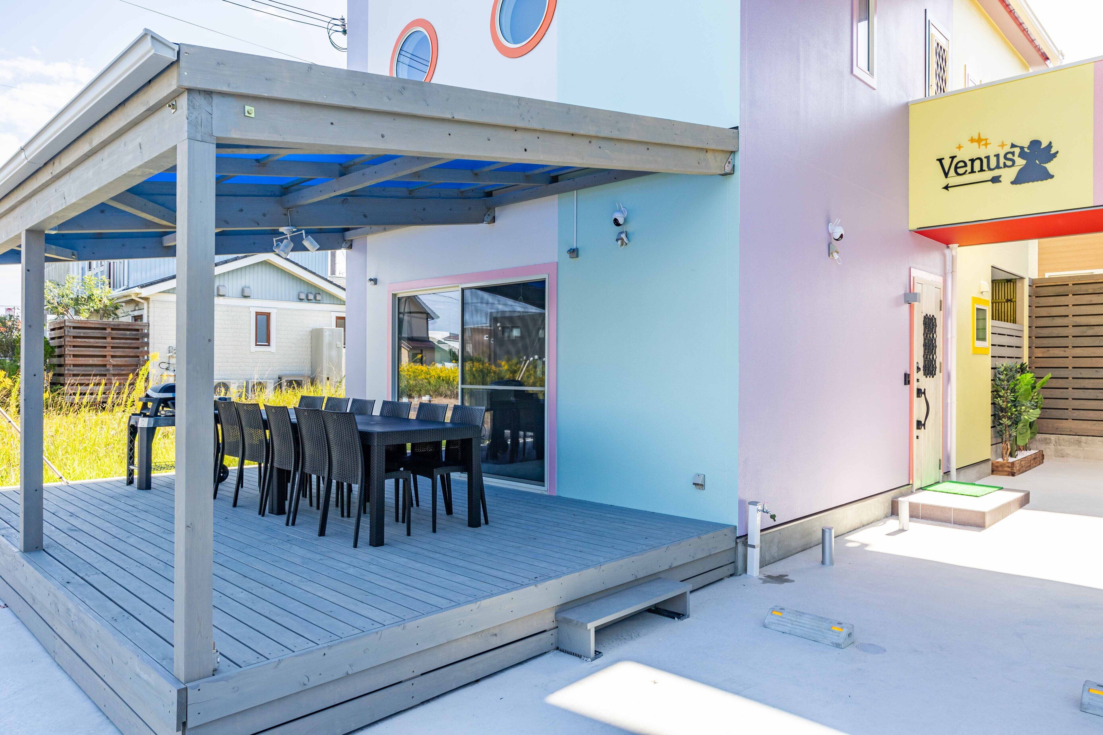 A covered outdoor seating area with a table and chairs, adjacent to a building with a 'Venus' sign.