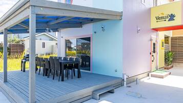A covered outdoor seating area with a table and chairs, adjacent to a building with a 'Venus' sign.