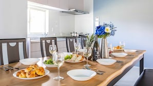 A dining table set with plates, croissants, wine glasses, and a vase with flowers.
