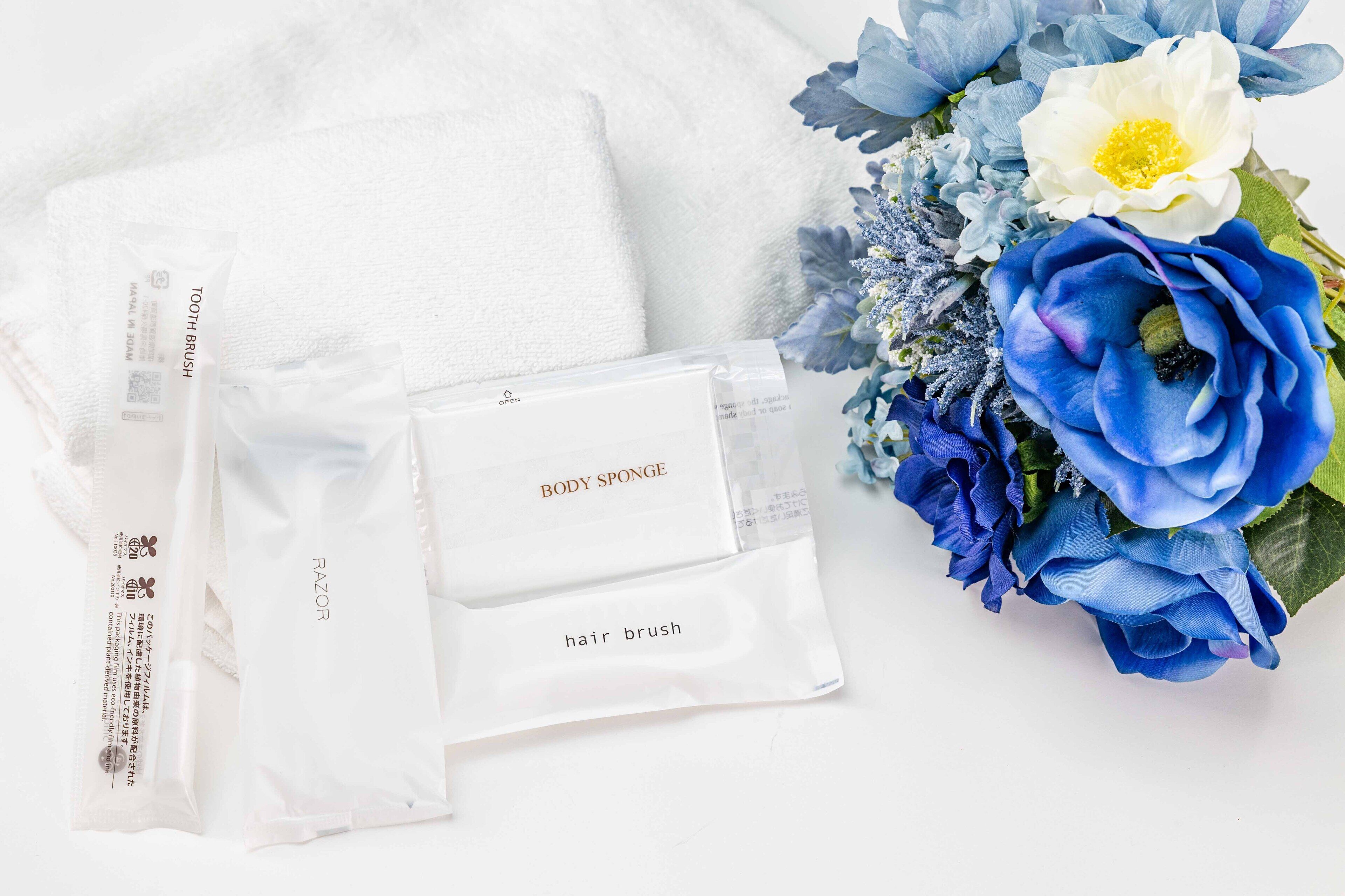 A white towel, a body sponge, a hair brush, and a bouquet of flowers.