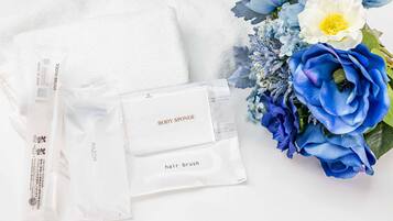 A white towel, a body sponge, a hair brush, and a bouquet of flowers.