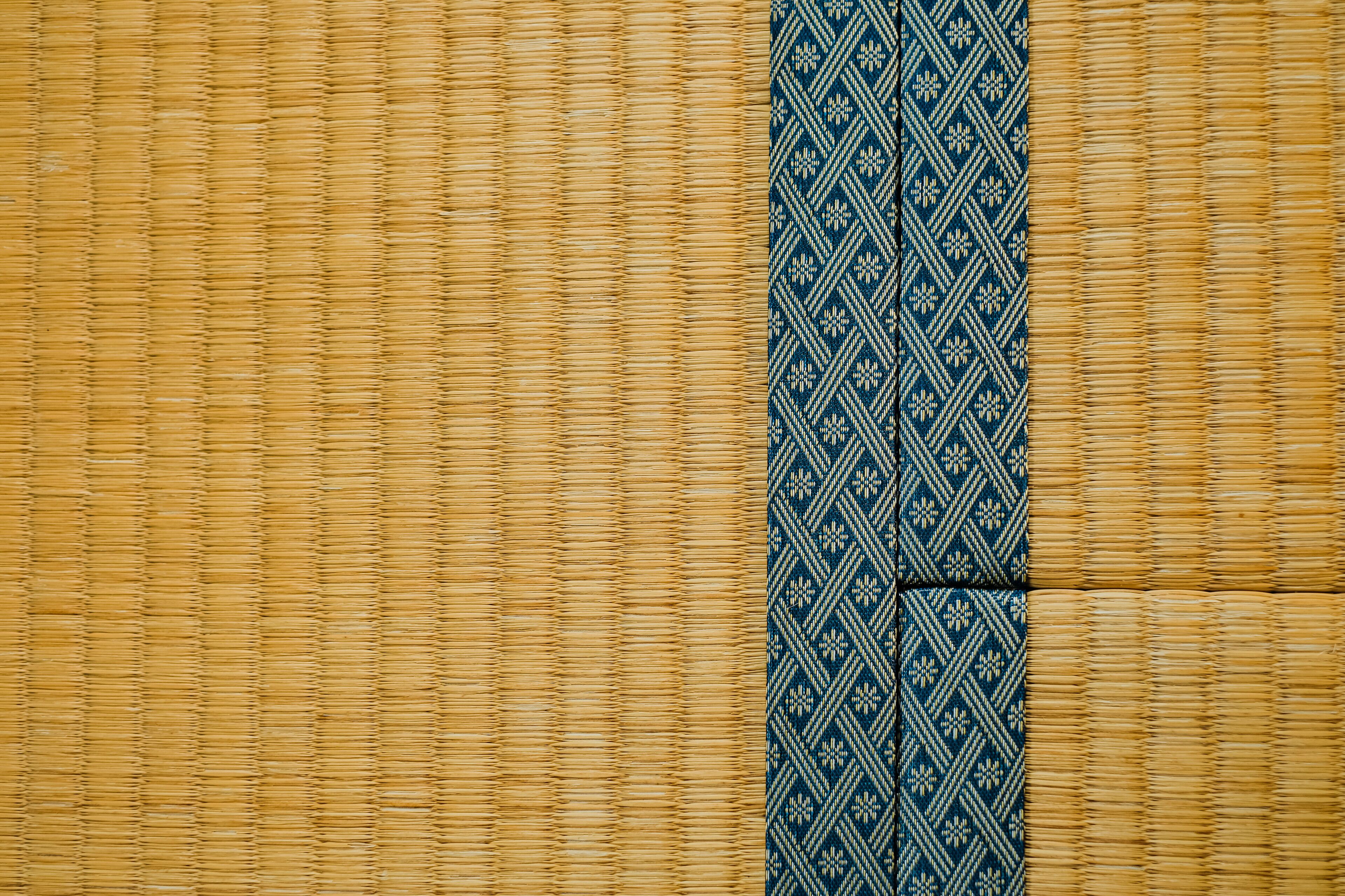 Un tapis en bambou tressé, orné d’une bordure à motifs bleus.