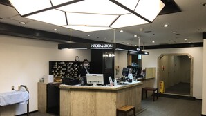 A reception area with a counter, computers, and a wall-mounted information sign. - Hotel 28 Hiroshima (Hiroshima)