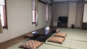 A traditional tatami mat room with a low table, cushions, a television, and a fireplace. - Hotel 28 Hiroshima (Hiroshima)