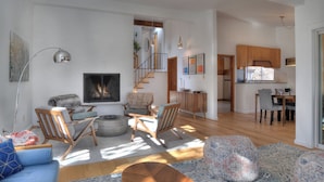 A modern living room with a fireplace, wooden furniture, and a staircase leading to a kitchen. - Mid Century Mtn Home and a cabin on 3 acres - 10 Min to DGO - AC-Hot Tub (Durango)
