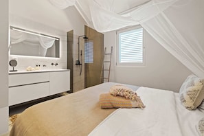 Relax in this serene bedroom with a large bed, bedside table, and natural light pouring in through the large window.