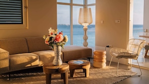 A living room with a sofa, a small wooden table, a vase with flowers, a lamp, and a chair.