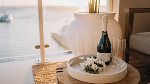 A bottle of Salentein wine on a tray with glasses and white flowers, set on a wooden table with a view of the sea.