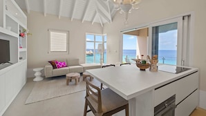 A modern kitchen with a large island, white cabinetry, and a view of the ocean.