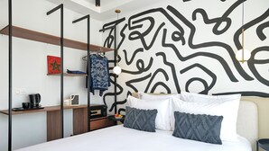 A modern hotel room with a bed, a desk, a coffee maker, and a wall with abstract art. - StayHere Rabat - Agdal Boutique Hotel (Rabat)