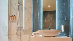 A modern bathroom with a glass-enclosed shower, a white sink with a vessel basin, and marble walls. - StayHere Rabat - Agdal Boutique Hotel (Rabat)