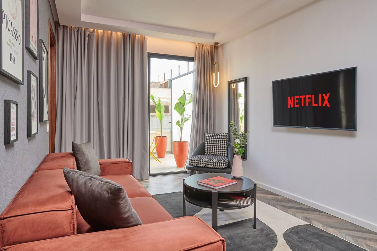 A modern living room with a sofa, a chair, a coffee table, and a TV displaying "NETFLIX".