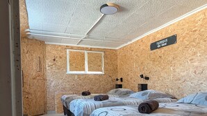 Habitació amb tres llits, un ventilador de sostre i un cartell que diu "FABRIQUE des Neuvons".